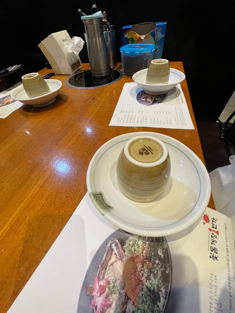 Seated with cup, plate, dried seaweed, tissues, and tools to eat crabs