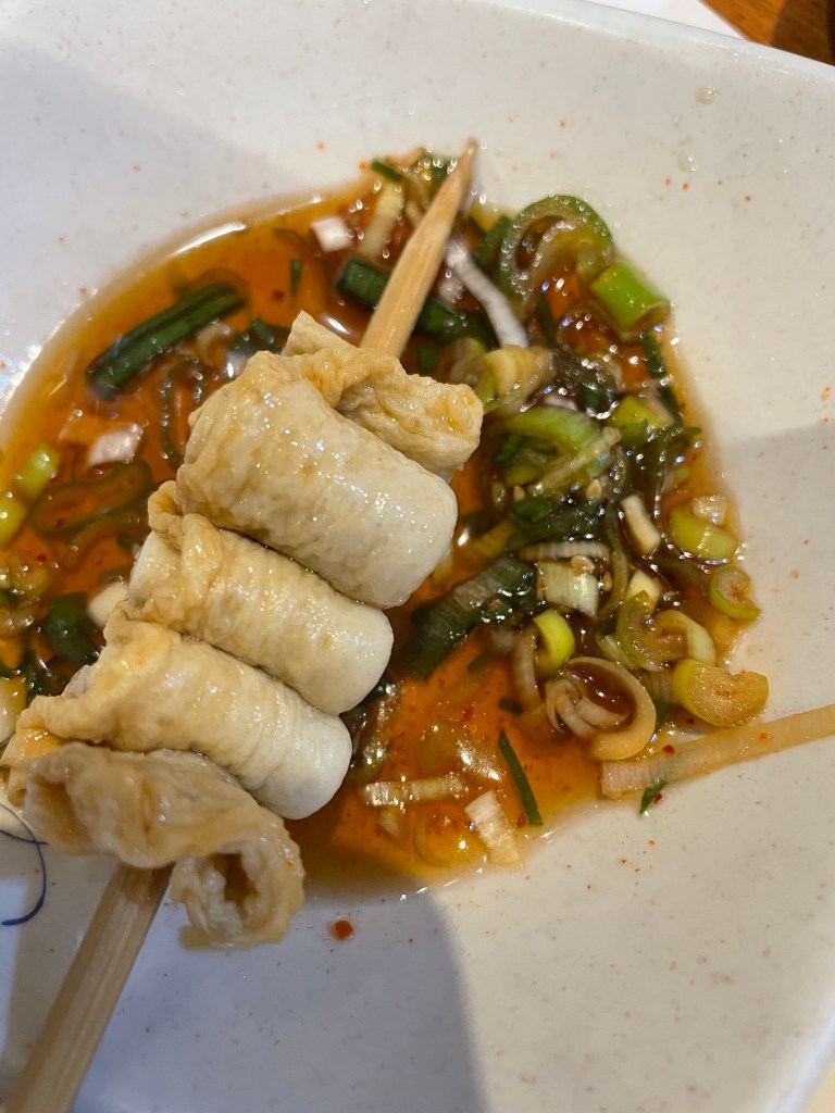 Dipping the fish cake skewer in soy sauce